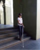 Persona bajando escaleras guindose con bastn largo.